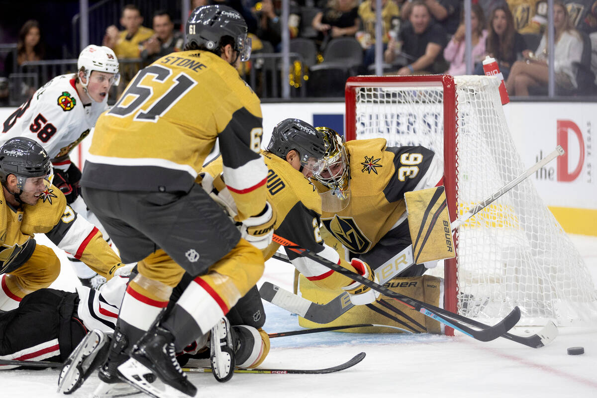 Golden Knights right wing Mark Stone (61) and defenseman Zach Whitecloud (2) knock the puck awa ...