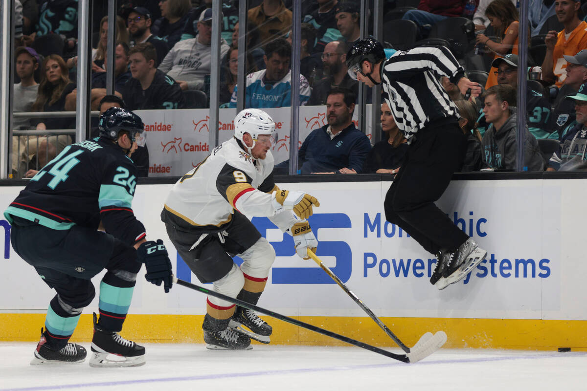 An official jumps out of the way as Seattle Kraken defenseman Jamie Oleksiak (24) and Vegas Gol ...