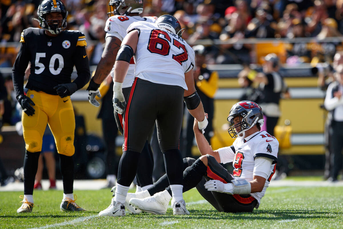 Tampa Bay Buccaneers quarterback Tom Brady (12) is helped up by teammate guard Luke Goedeke (67 ...