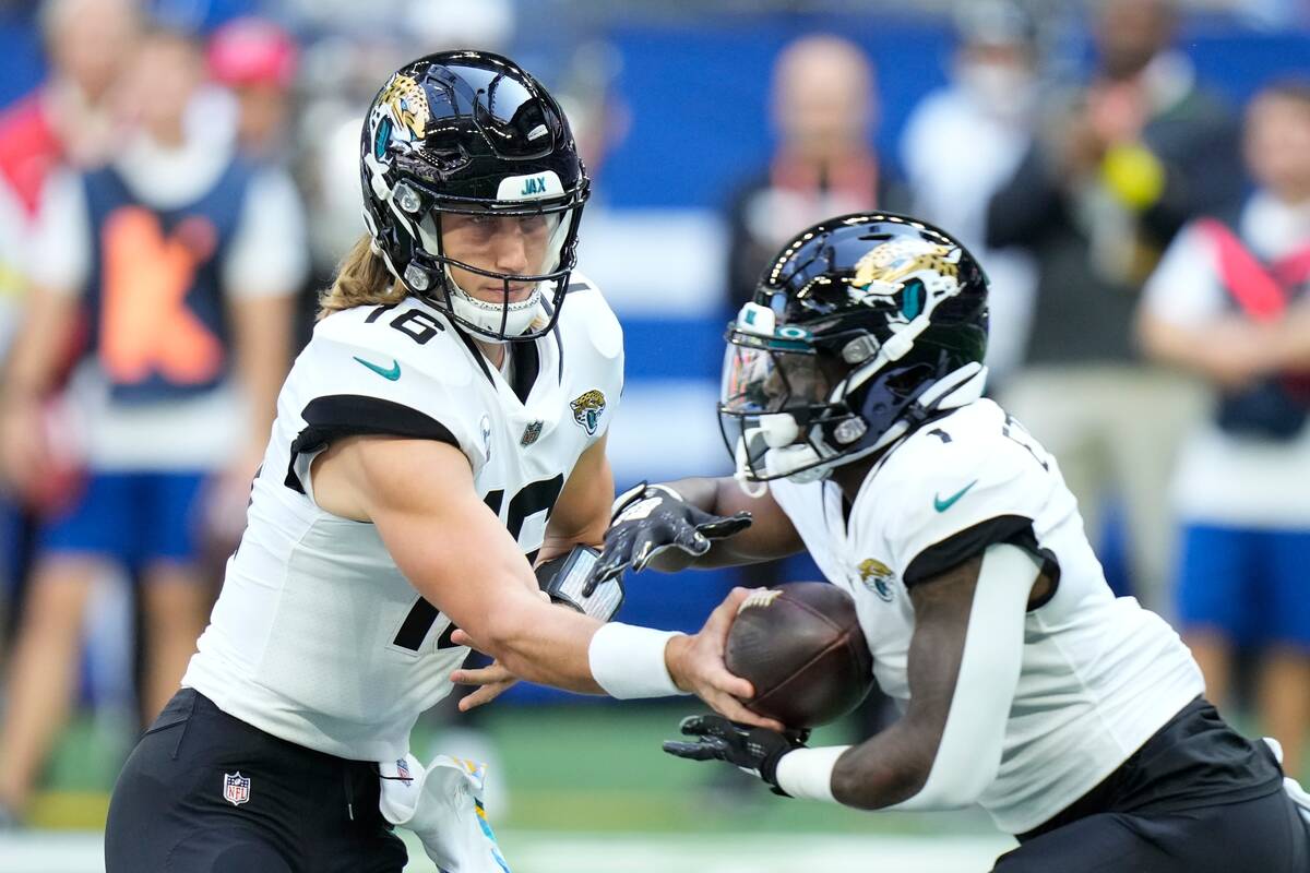 Jacksonville Jaguars quarterback Trevor Lawrence (16) hands off to running back Travis Etienne ...