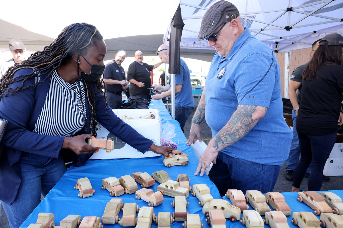 Alberta Obodai of Las Vegas buys toy cars from Tom Ratzsch during an Injured Police Officers Fu ...