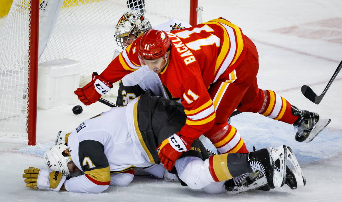 Vegas Golden Knights goalie Logan Thompson, center, looks back as Calgary Flames forward Mikael ...