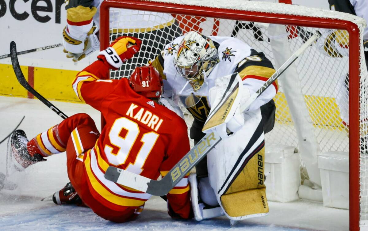 Vegas Golden Knights goalie Logan Thompson, right, falls back into the net as Calgary Flames fo ...