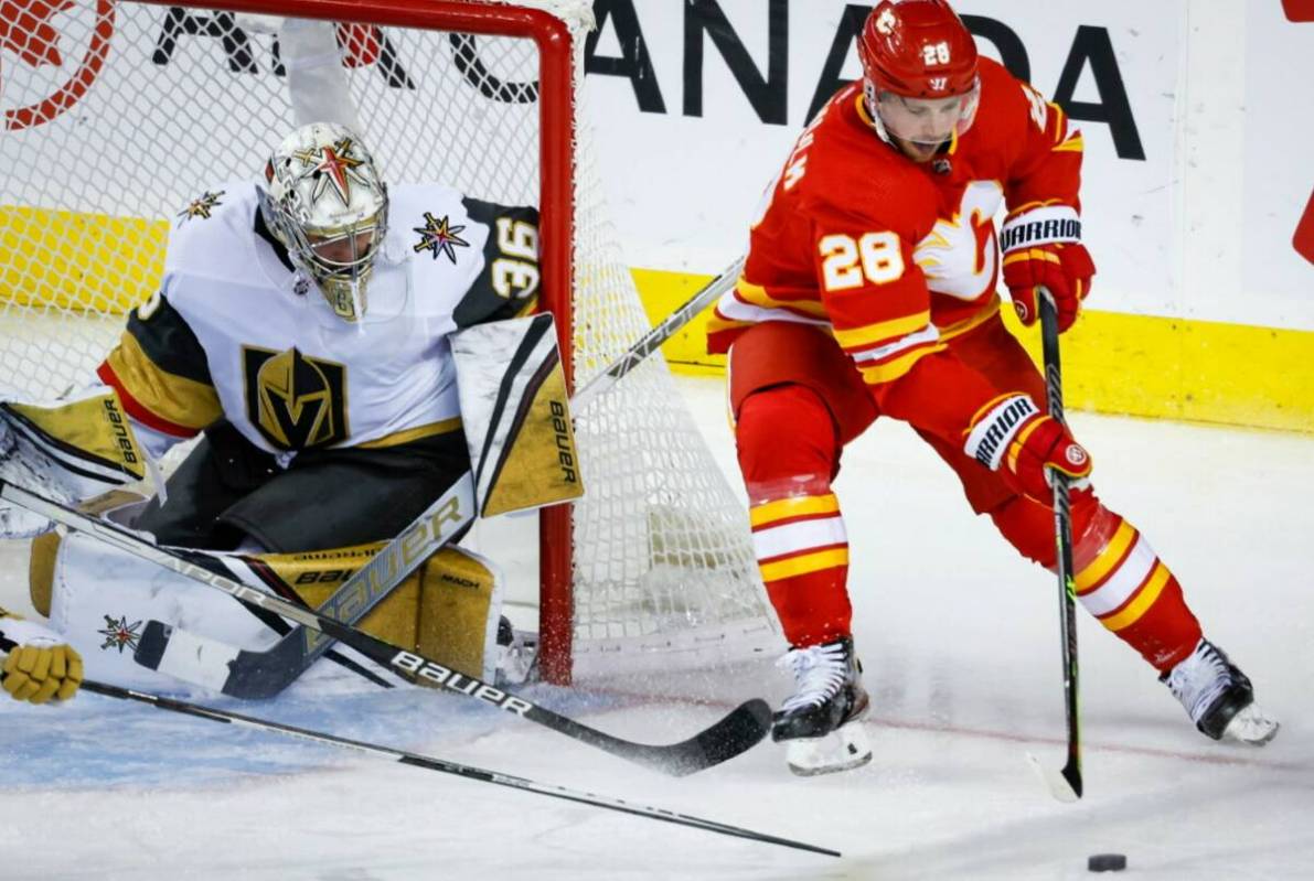 Vegas Golden Knights goalie Logan Thompson, left, watches as Calgary Flames forward Elias Lindh ...