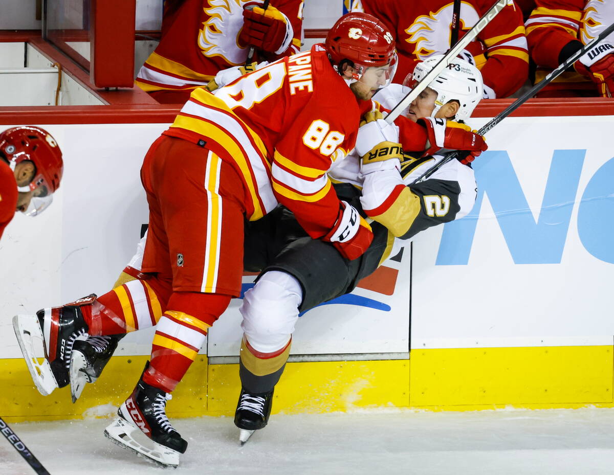 Vegas Golden Knights defenseman Zach Whitecloud, right, is checked by Calgary Flames forward An ...