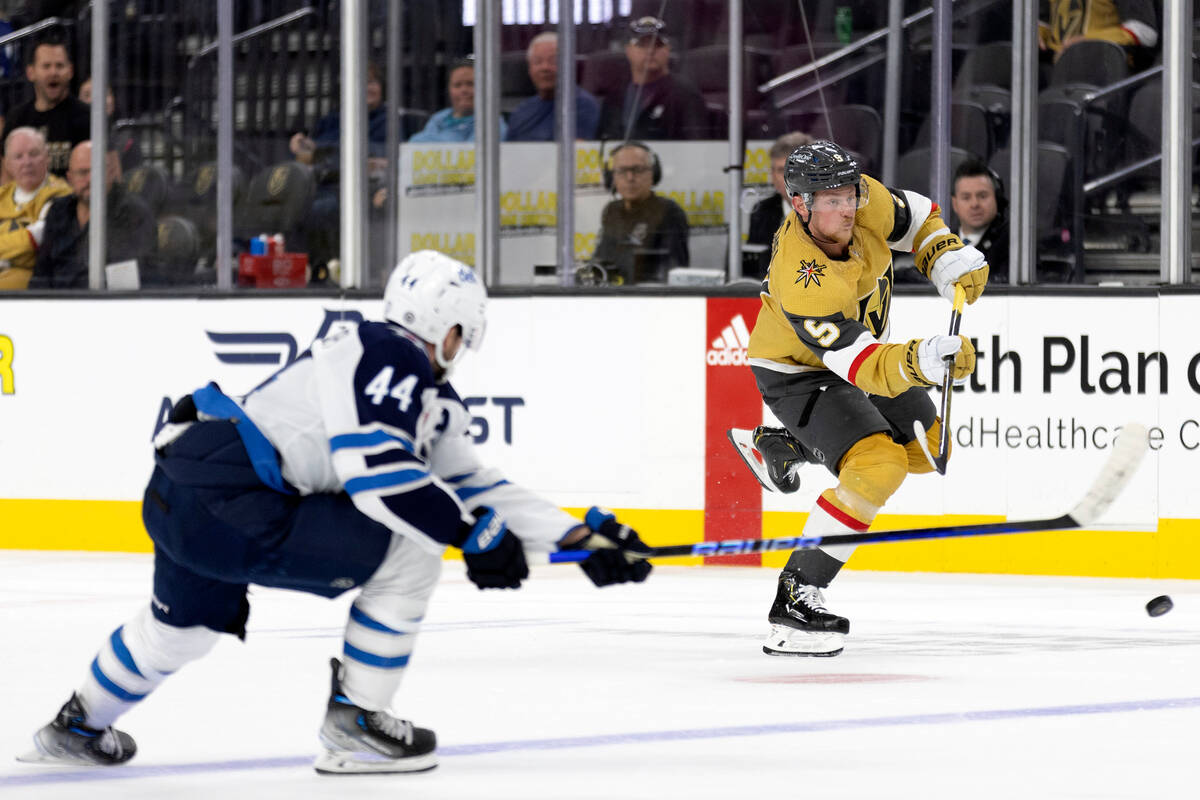 Golden Knights center Jack Eichel (9) takes a shot on the empty goal while Jets defenseman Josh ...