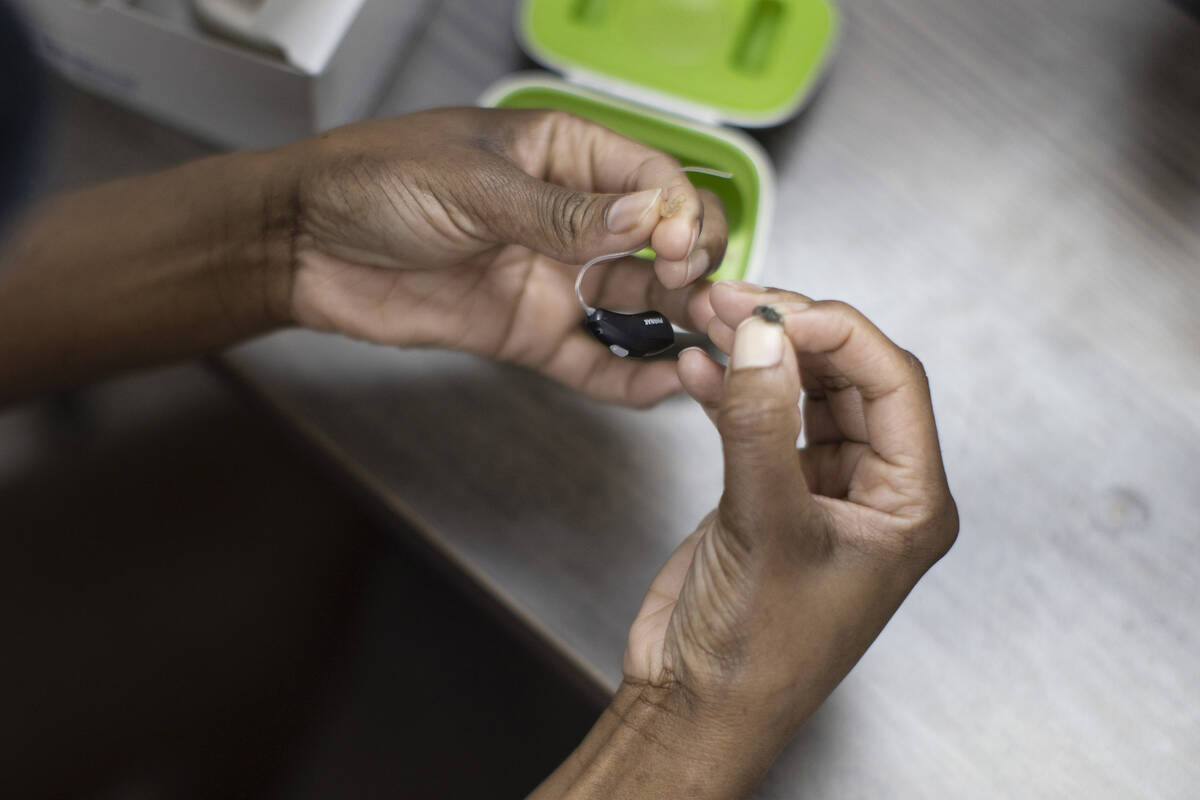 A patient holds her hearing aid as she visits Hear Again America for a checkup on Oct. 20, 2021 ...