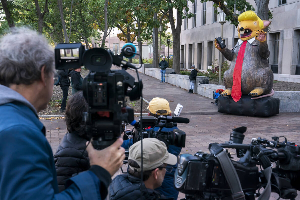 Media gathers around an inflatable rat styled after former President Donald Trump while waiting ...