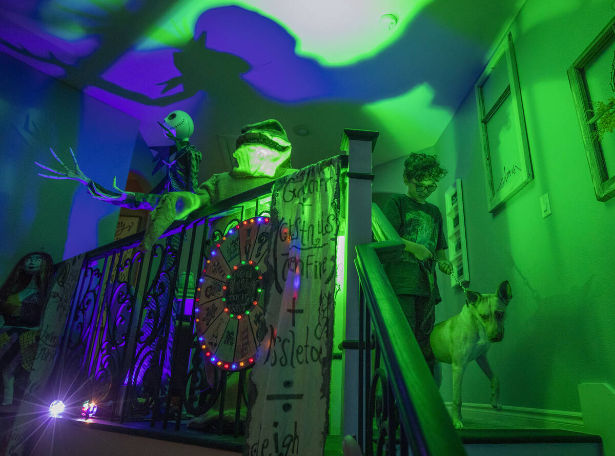 Evan Garcia, 10, walks his dog Jessie down the stairs of their Disney Halloween themed home, in ...