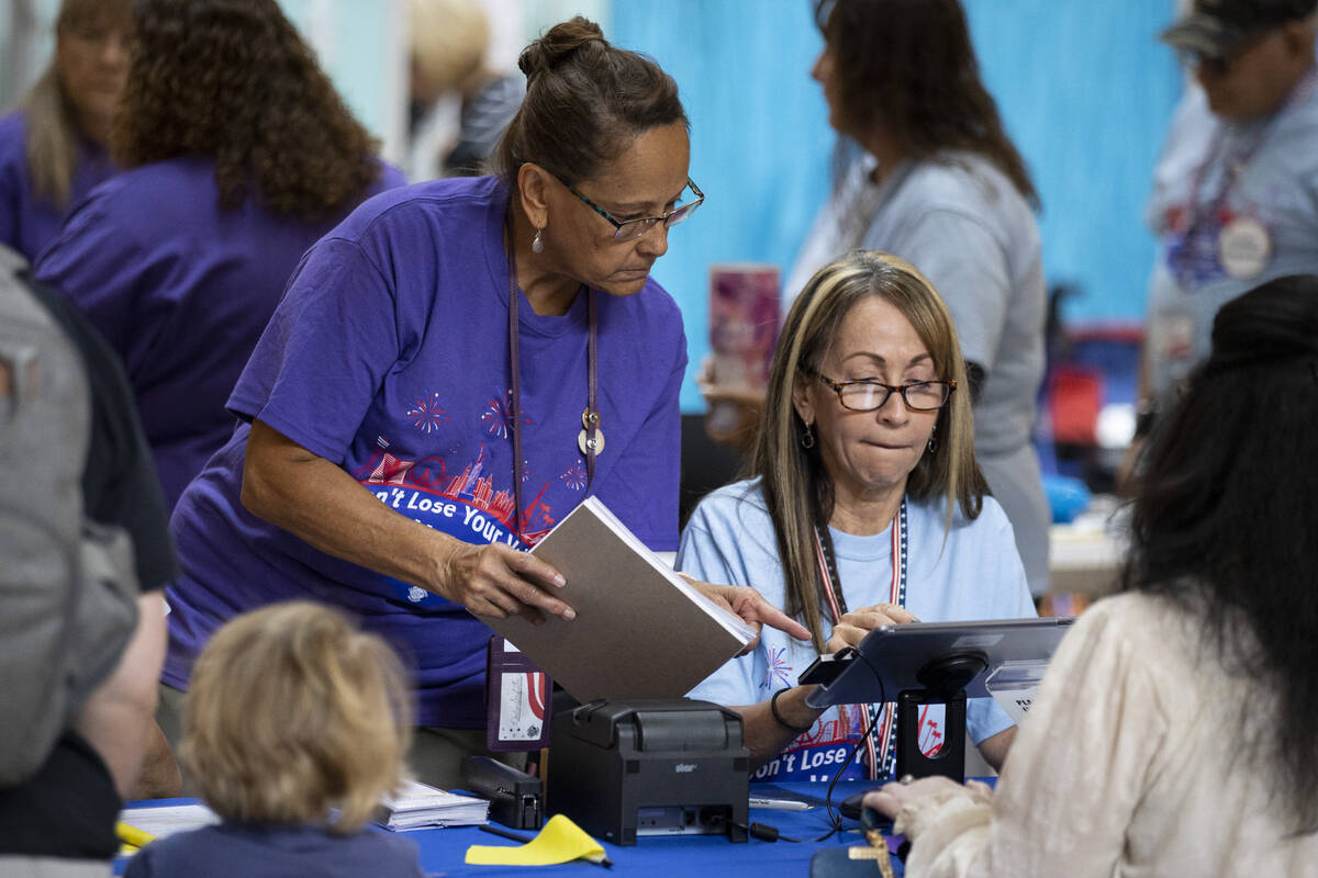 Poll workers Brigitte Benadi-Reaney, left, and Nadine Singleton, assist a voter at the polling ...