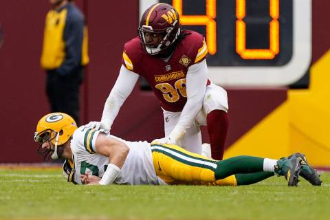 Green Bay Packers quarterback Aaron Rodgers (12) lays on the turf with Washington Commanders de ...