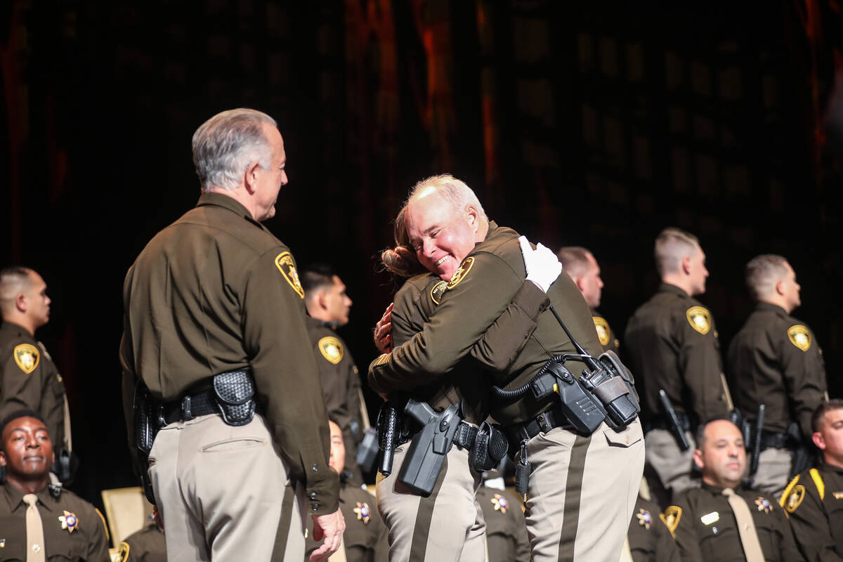 Officer Stephen Kircher, right, hugs his daughter and academy graduate Kirsten Kircher, center, ...
