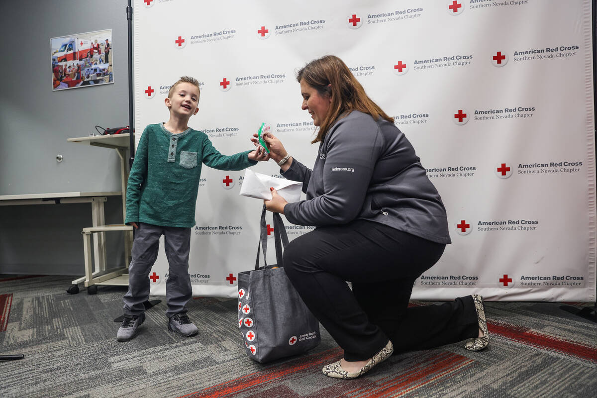 Henry Williams, 6, left, hands his donation to Rachel Flanigan, executive director of the Red C ...