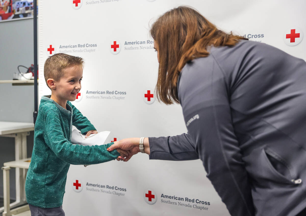 Henry Williams, 6, left, shakes hands with Rachel Flanigan, executive director of the Red Cross ...