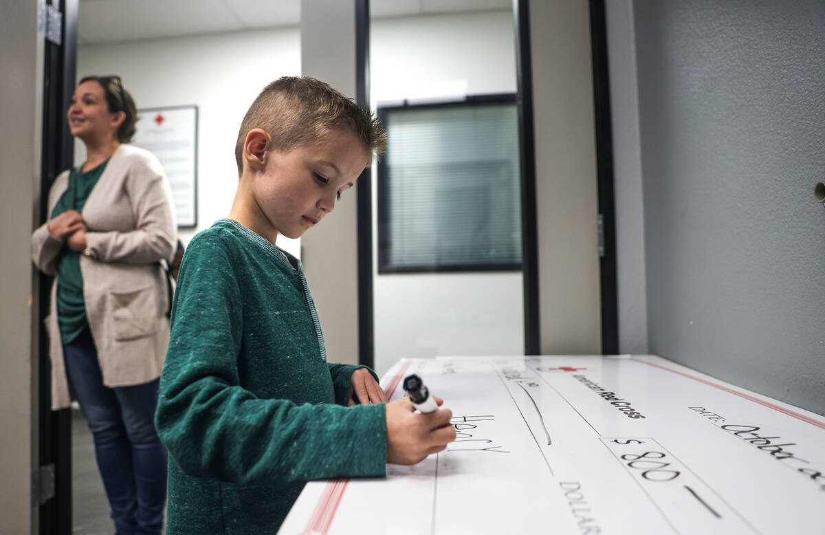 Henry Williams, 6, signs a check of $800 for the American Red Cross at the Red Cross of Souther ...