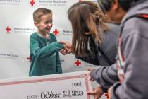 Henry Williams, 6, left, shakes hands with Rachel Flanigan, executive director of the Red Cross ...