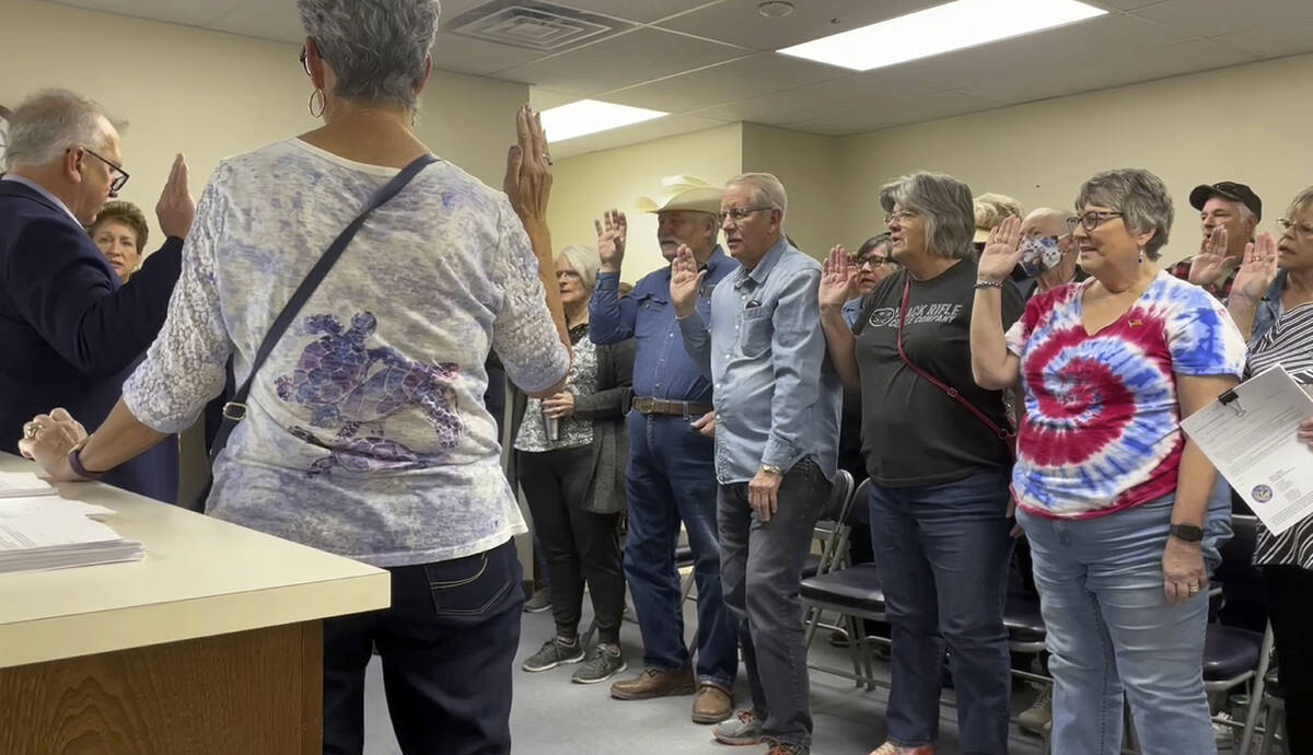 In this image from video, Nye County Clerk Mark Kampf, far left, in suit, swears in a group of ...