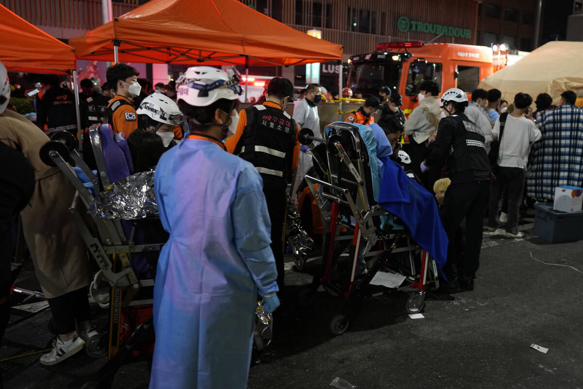 Rescue workers carry injuried people at the street near the scene in Seoul, South Korea, early ...