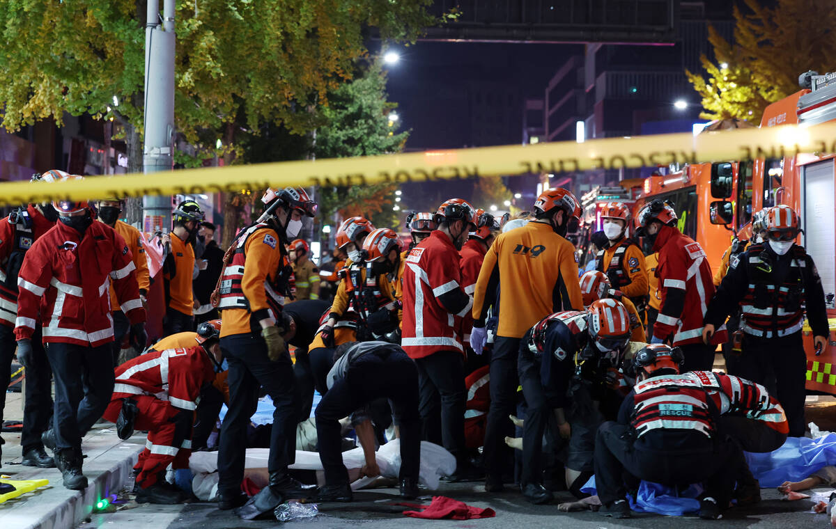 Rescue workers and firefighters work on the scene of a crushing accident in Seoul, South Korea, ...