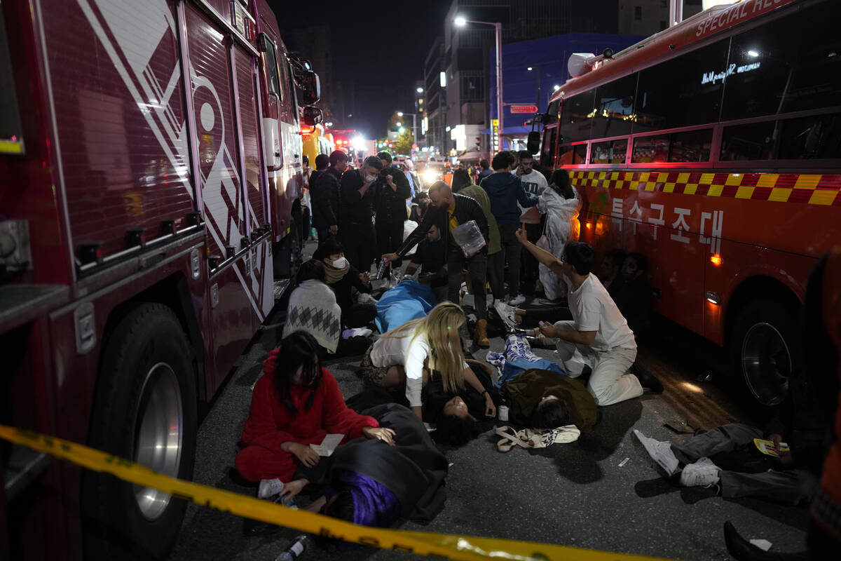 Injuried people are helped at the street near the scene in Seoul, South Korea, early Sunday, Oc ...