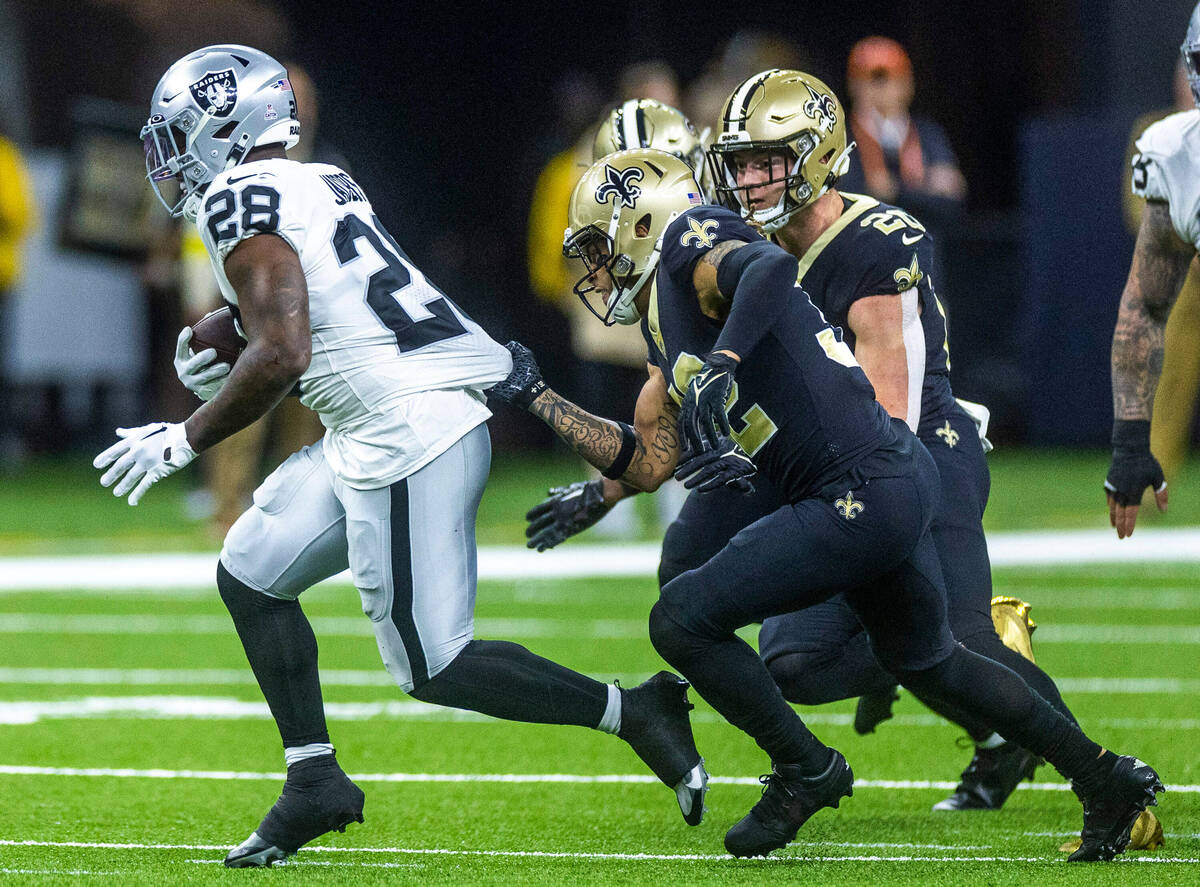 Raiders running back Josh Jacobs (28) is grabbed by his jersey by New Orleans Saints safety Tyr ...