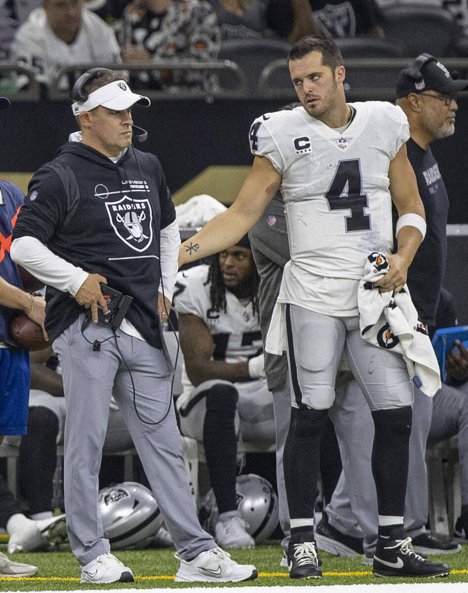 Raiders quarterback Derek Carr (4) tries to speak to head coach Josh McDaniels during the secon ...