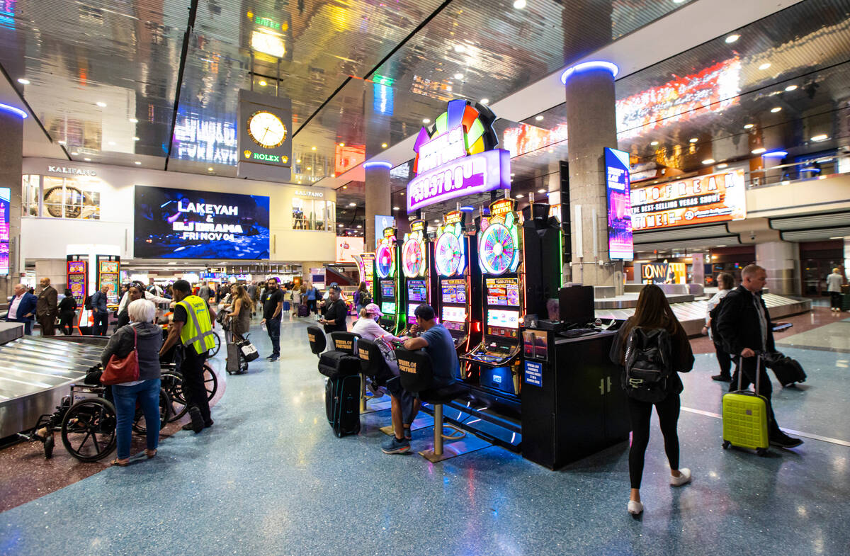 Travelers pass by slot machines in the Terminal 1 baggage claim area at Harry Reid Internationa ...