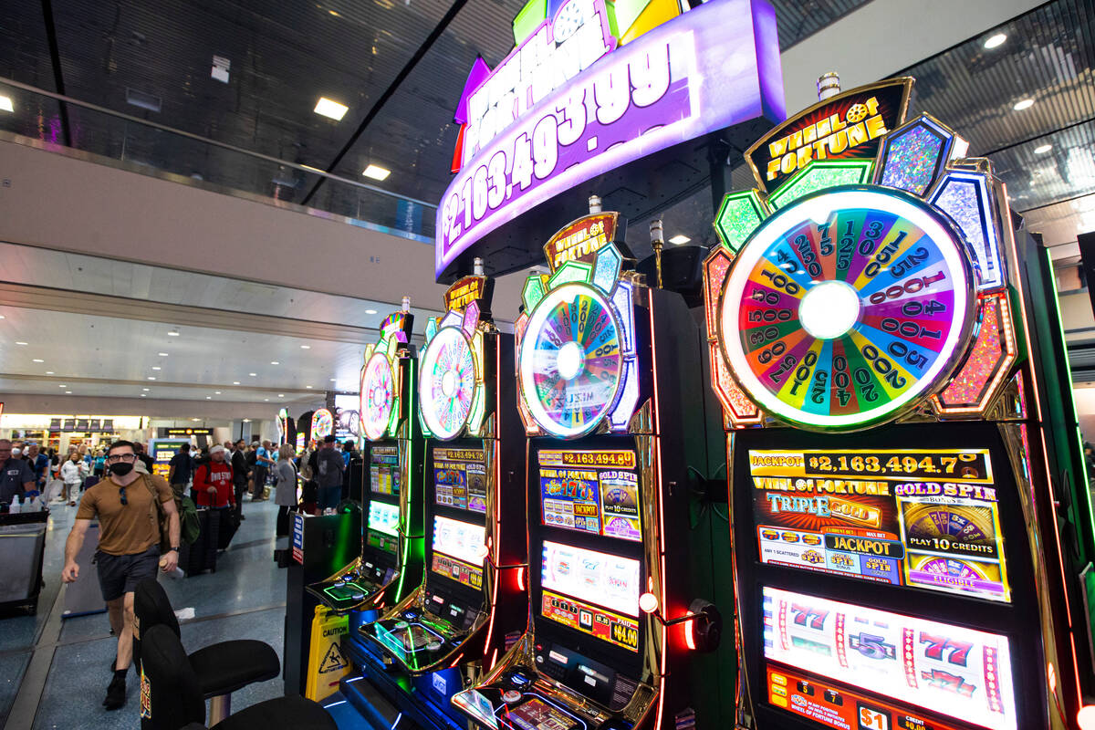 Travelers pass by slot machines in the Terminal 1 baggage claim area at Harry Reid Internationa ...
