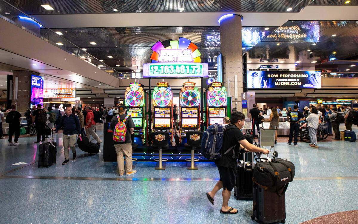 Travelers pass by slot machines in the Terminal 1 baggage claim area at Harry Reid Internationa ...