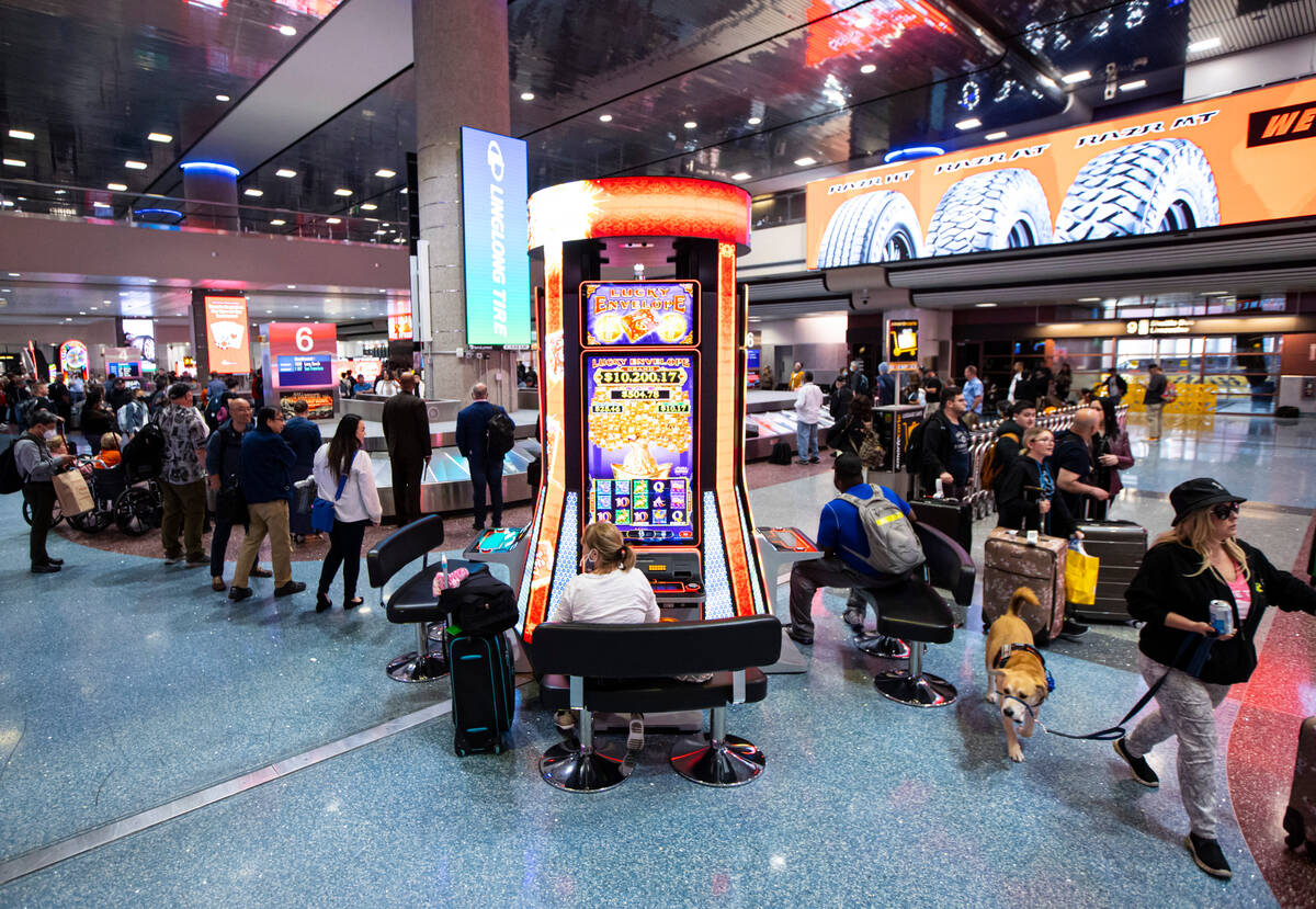 Travelers sit by slot machines in the Terminal 1 baggage claim area at Harry Reid International ...