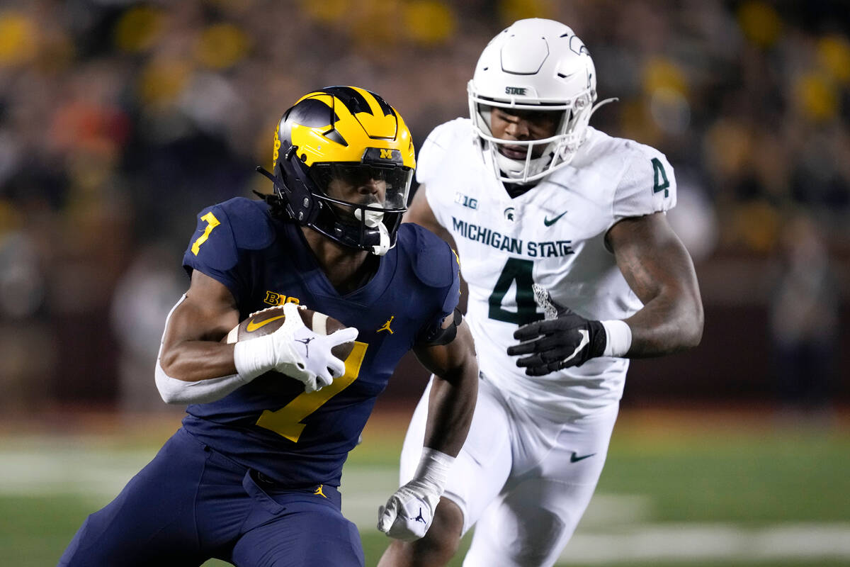 Michigan running back Donovan Edwards (7) runs the ball as Michigan State linebacker Jacoby Win ...