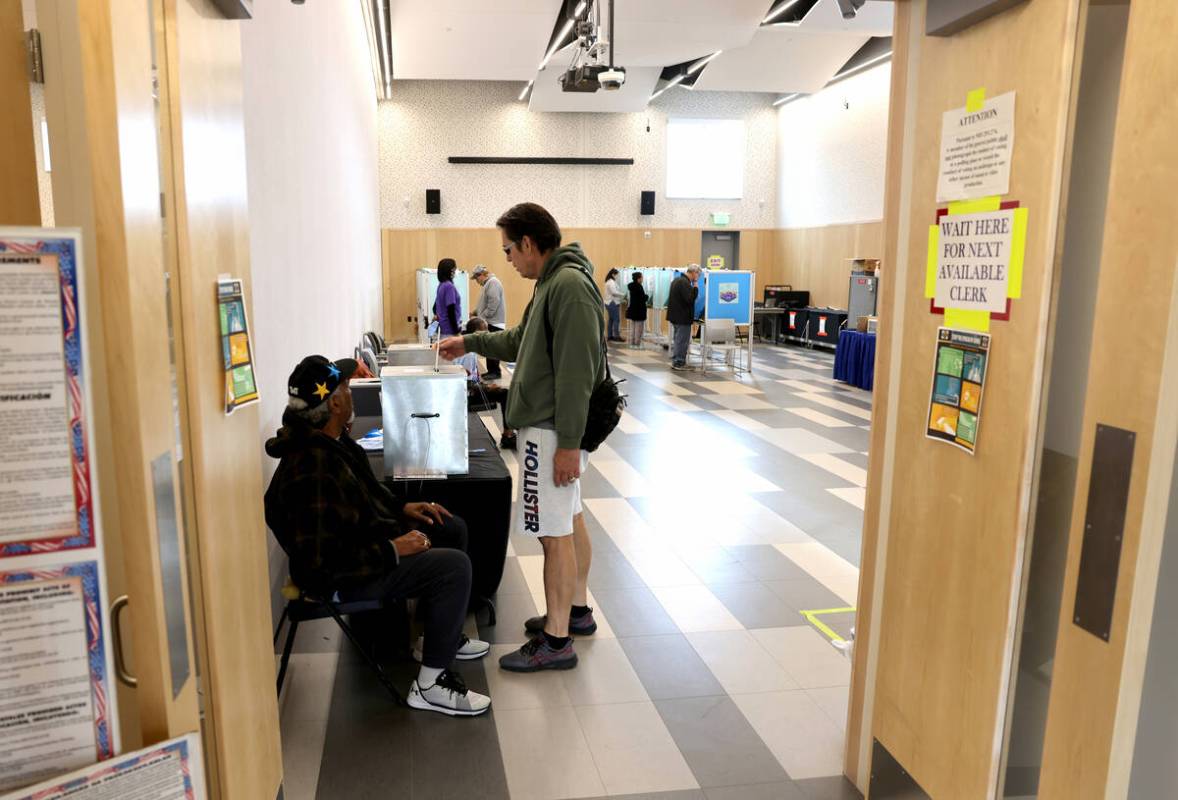 Mark Stieb of Las Vegas drops his ballot as poll worker William Redic looks on at East Las Vega ...