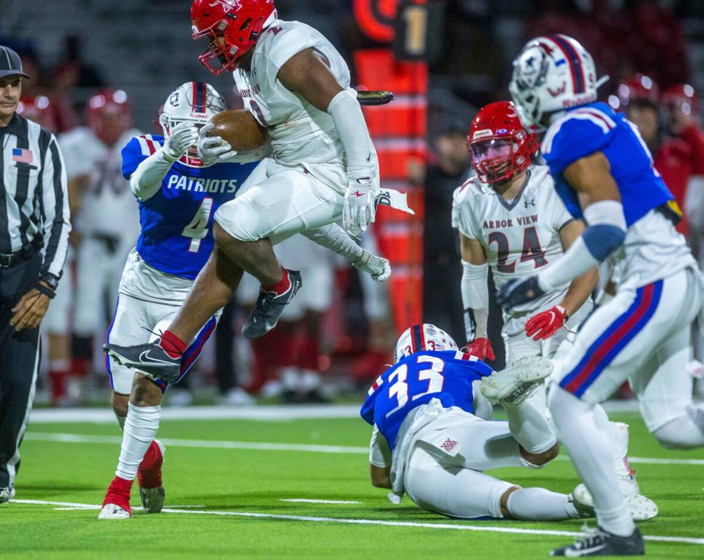 Arbor View RB Richard Washington (2) is met by Liberty SB Colin Gregorio (4) after leaping over ...