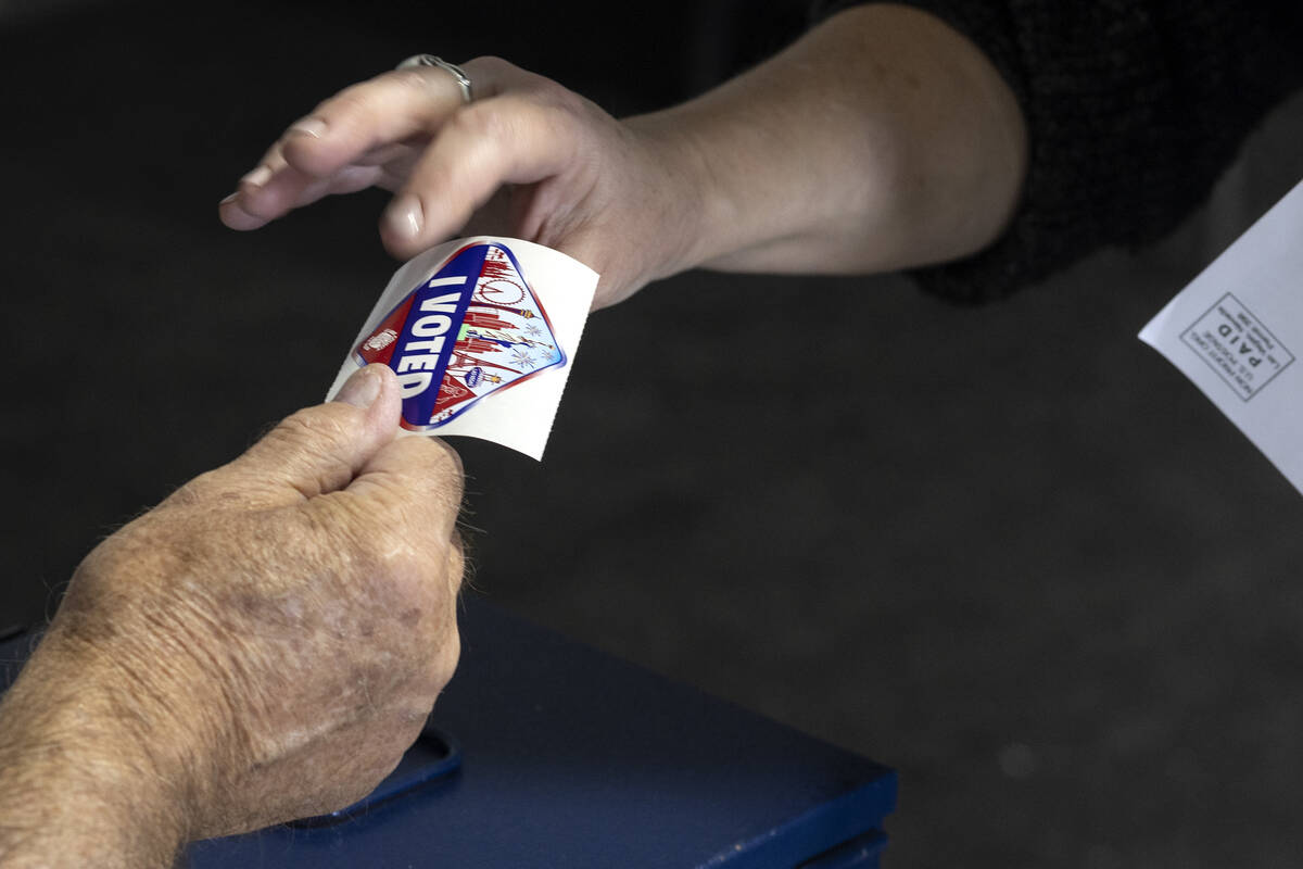 A voter accepts an I Voted Sticker on the last day of early voting, Friday, Nov. 4, 2022, at Si ...