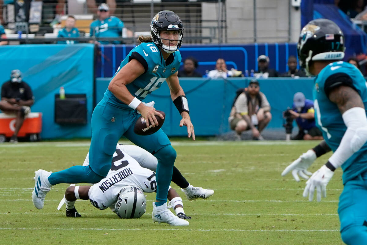 Jacksonville Jaguars quarterback Trevor Lawrence (16) scrambles away from Las Vegas Raiders cor ...