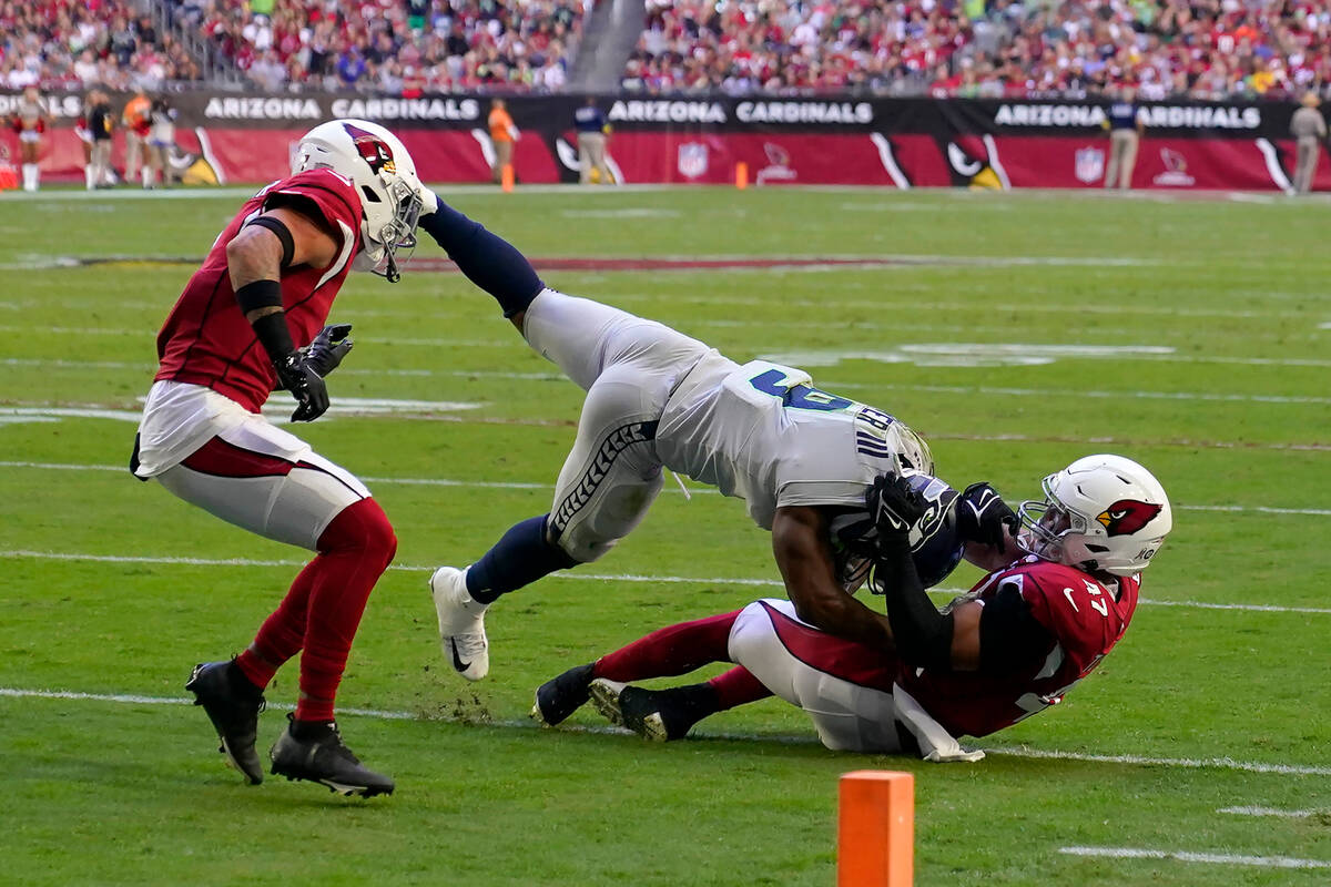 Seattle Seahawks running back Kenneth Walker III, middle, is tackled by Arizona Cardinals lineb ...