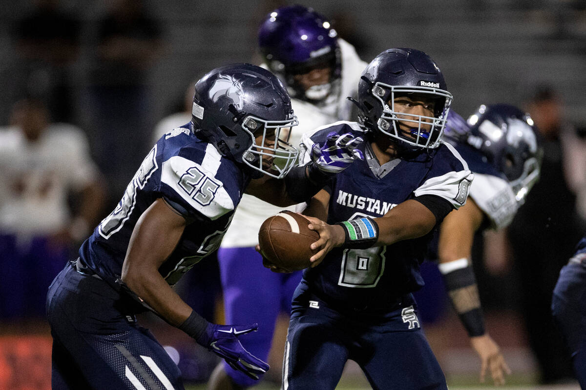 Shadow Ridge quarterback Coen Coloma (8) hands the ball off to running back JaQuieze Holland (2 ...