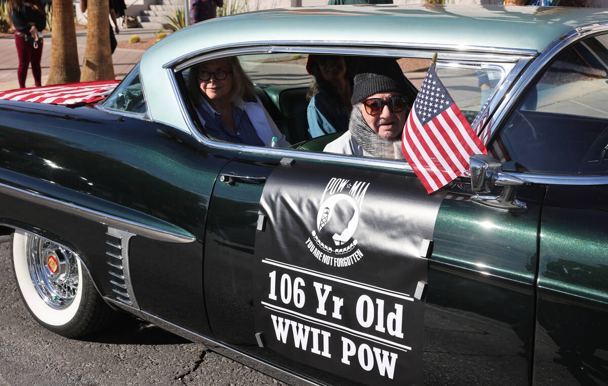 Vincent Shank, a World War II veteran and ex-POW, waves a flag before the Veterans Day parade o ...