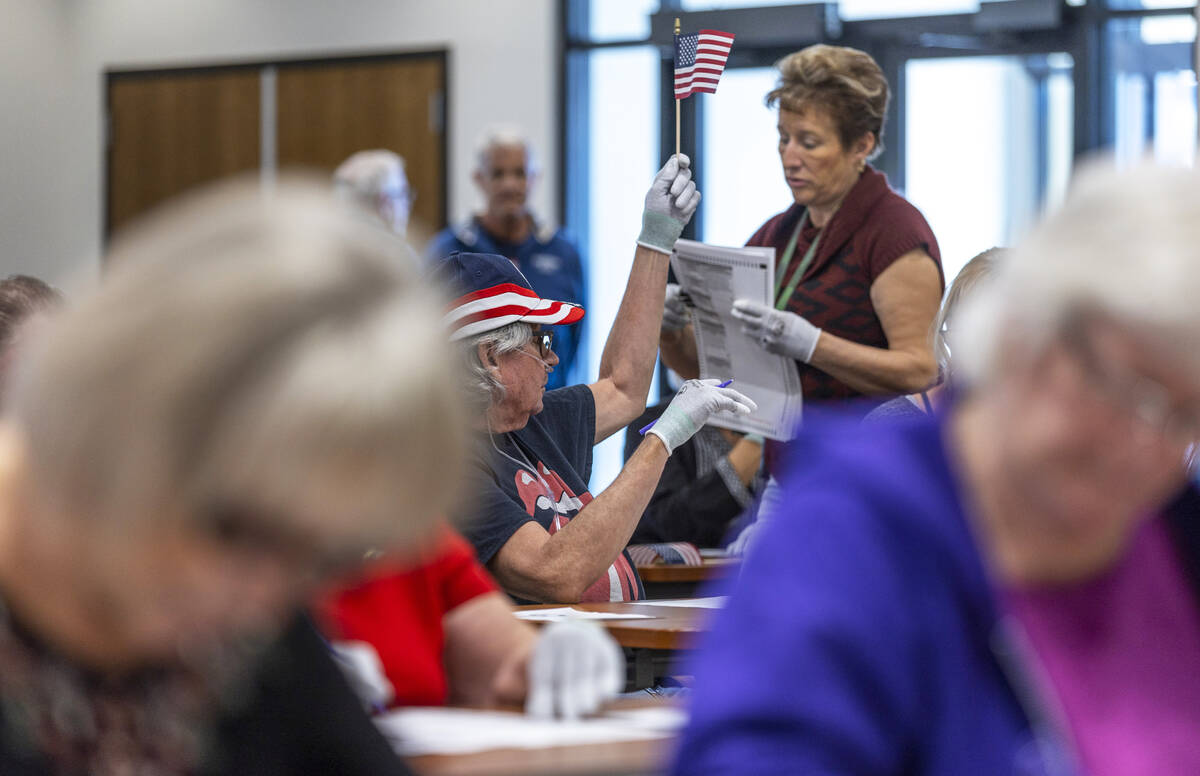 A volunteer waves a flag for ballot marking confirmation as they resume hand counting ballots i ...