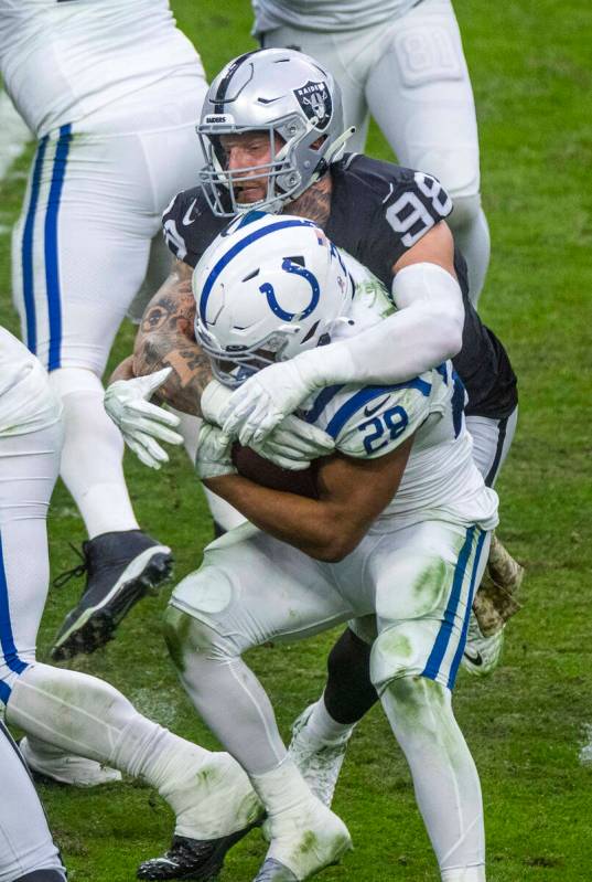 Raiders defensive end Maxx Crosby (98) wraps up Indianapolis Colts running back Jonathan Taylor ...