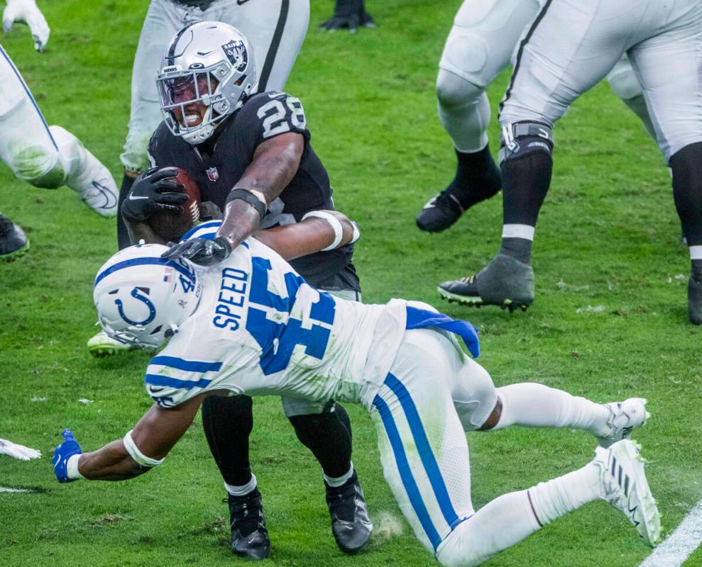 Raiders running back Josh Jacobs (28) fights off a tackle by Indianapolis Colts linebacker E.J. ...