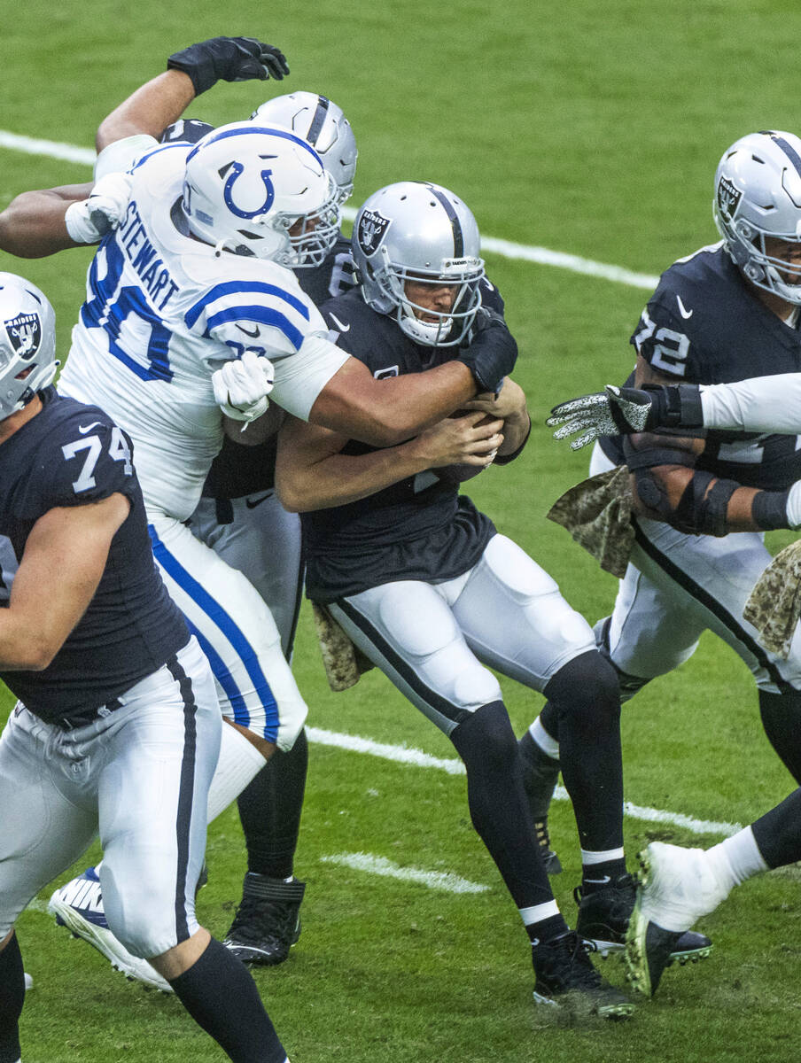 Raiders quarterback Derek Carr (4) is wrapped up for a sack by Indianapolis Colts defensive tac ...