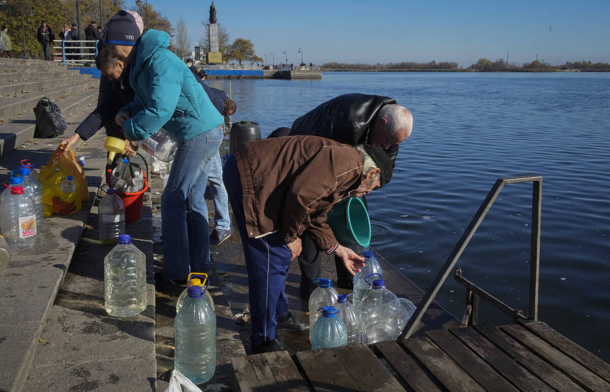 People collect water from a Dnipro river in Kherson, Ukraine, Tuesday, Nov. 15, 2022. Waves of ...