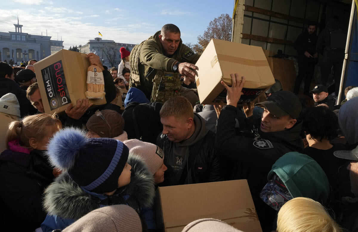 People receive humanitarian aid on central square in Kherson, Ukraine, Tuesday, Nov. 15, 2022. ...