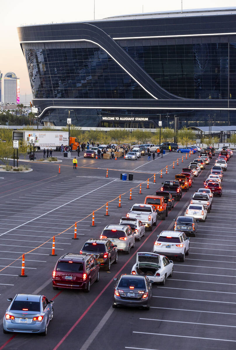 Cars weave their way around Allegiant Stadium as Raiders' current and former players along with ...