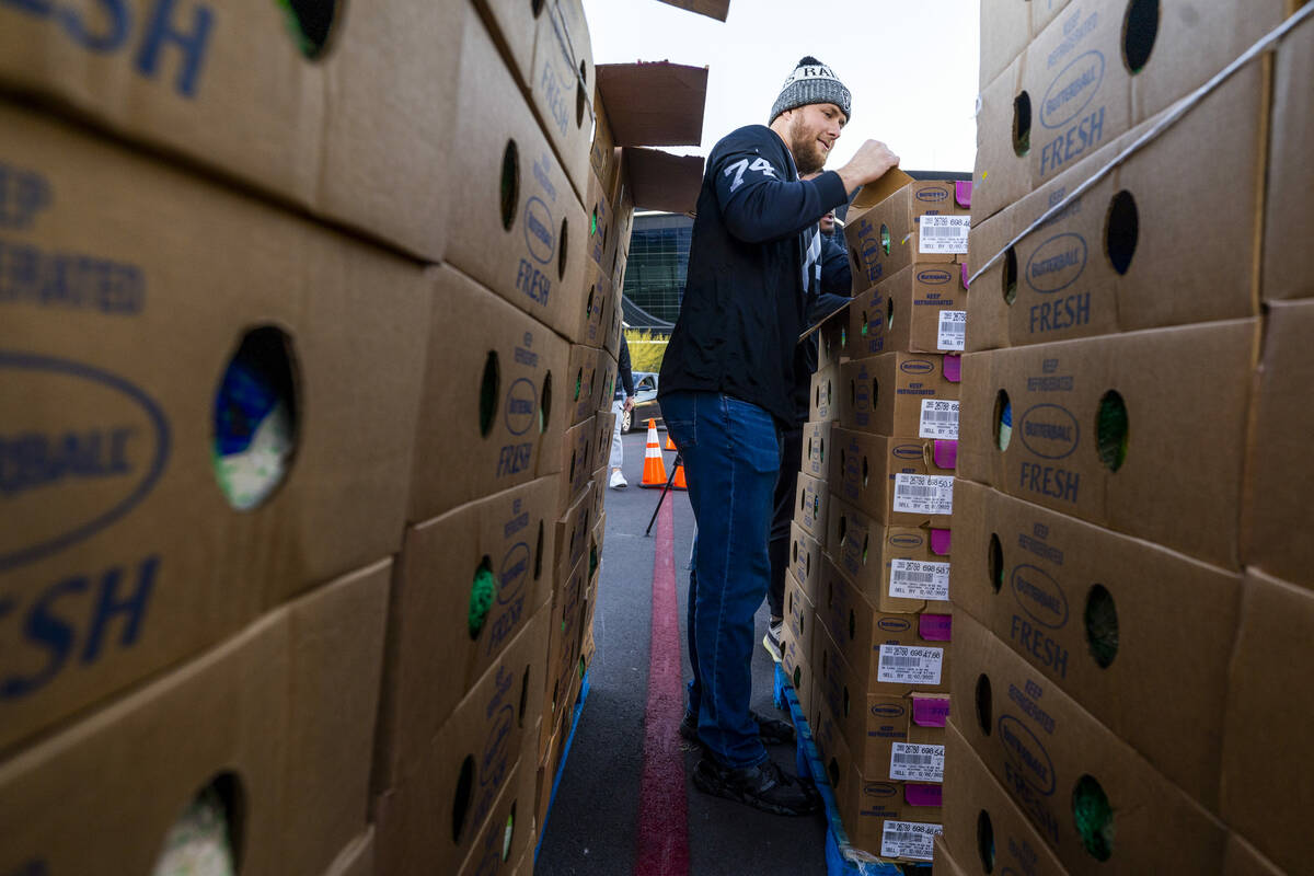 Raiders offensive tackle Kolton Miller (74) opens another box of turkeys as he joins current an ...