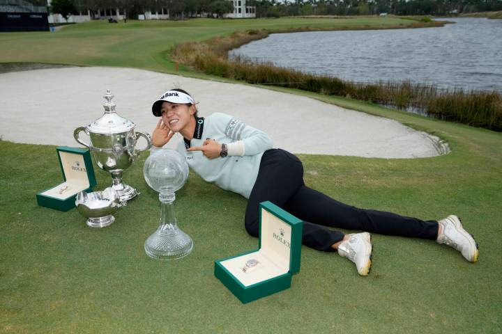 Lydia Ko, of New Zealand, poses with the Rolex Player of the Year trophy, left, the Vare trophy ...