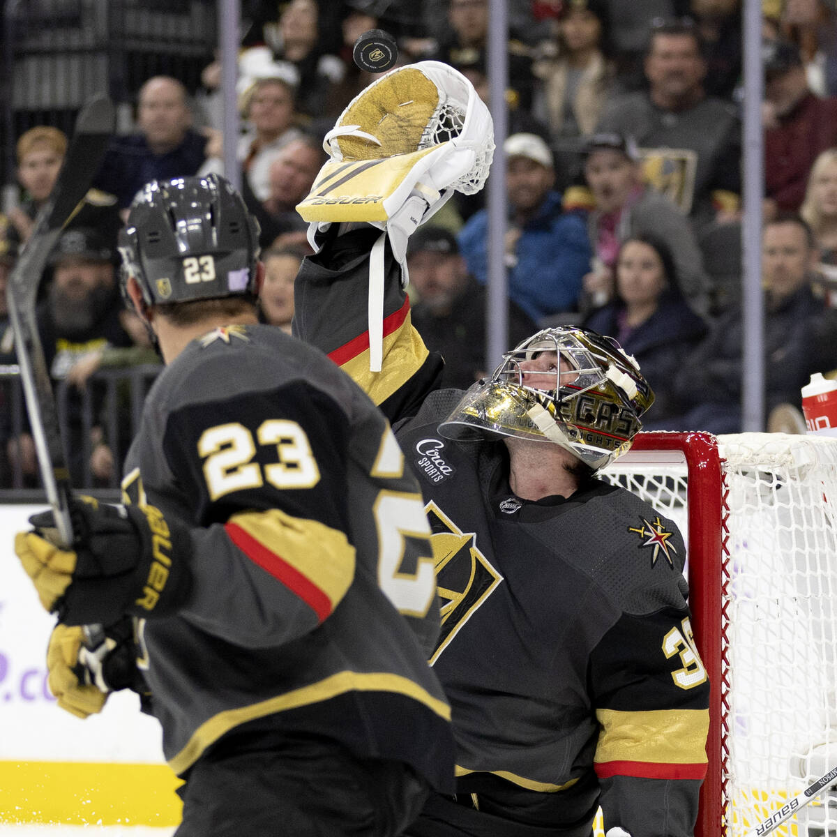 Golden Knights goaltender Logan Thompson (36) makes a glove save while defenseman Alec Martinez ...