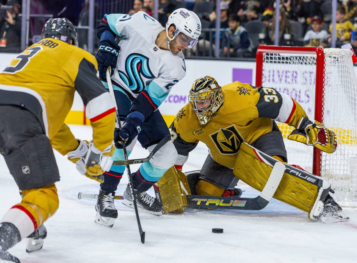 Golden Knights goaltender Adin Hill (33) defends the net from Seattle Kraken center Alex Wennbe ...