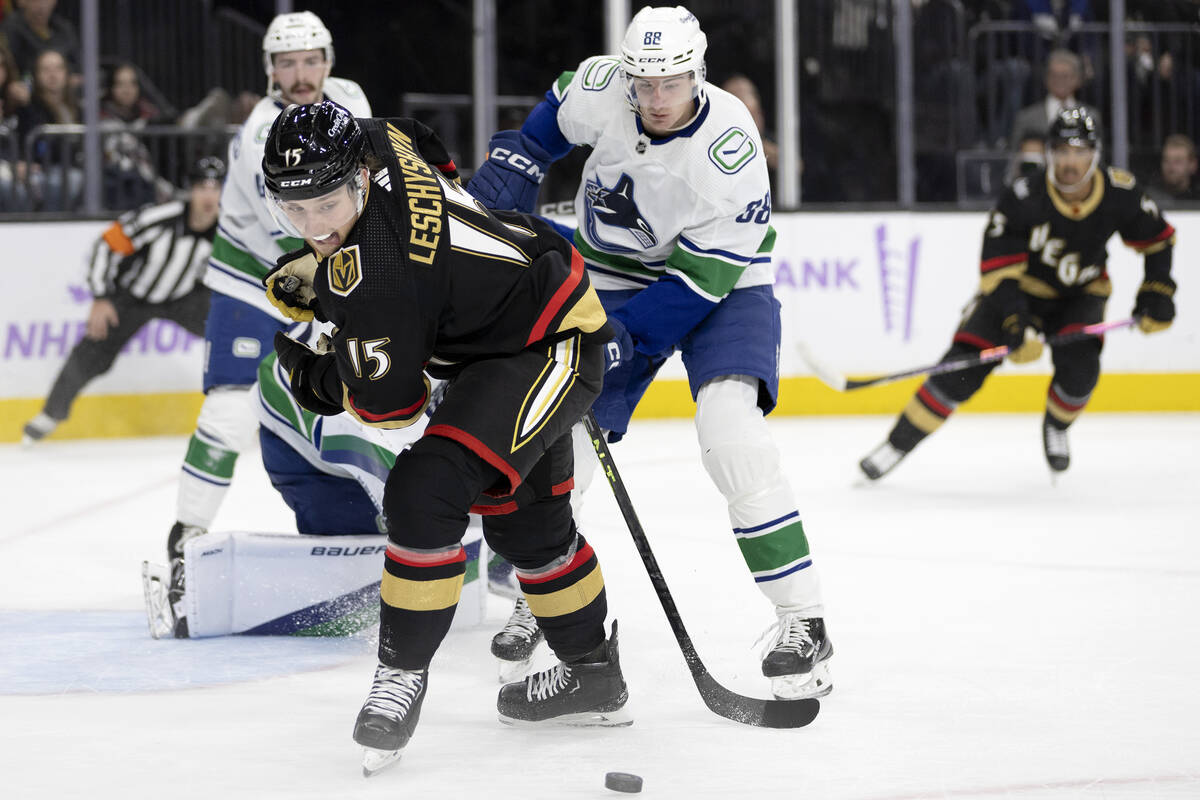 Golden Knights center Jake Leschyshyn (15) skates of the puck against Canucks center Nils Aman ...